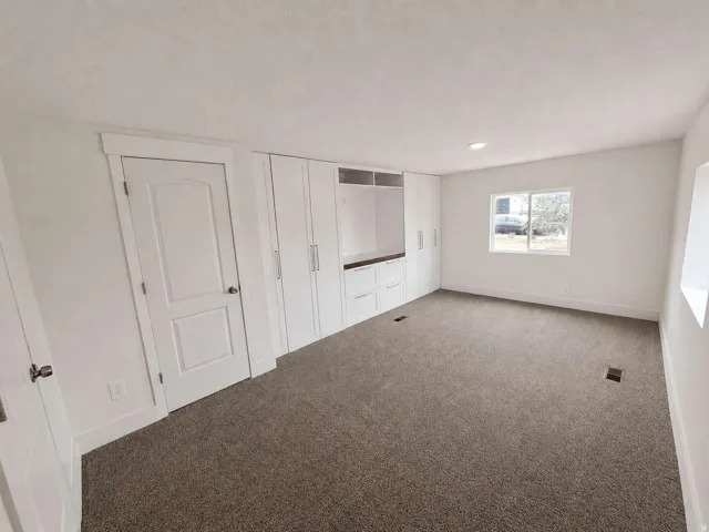 Wall-to-wall carpeting, recessed lighting, and a window with white trim