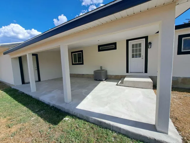 Covered outdoor patio with a concrete surface, white exterior walls, and black trim accents
