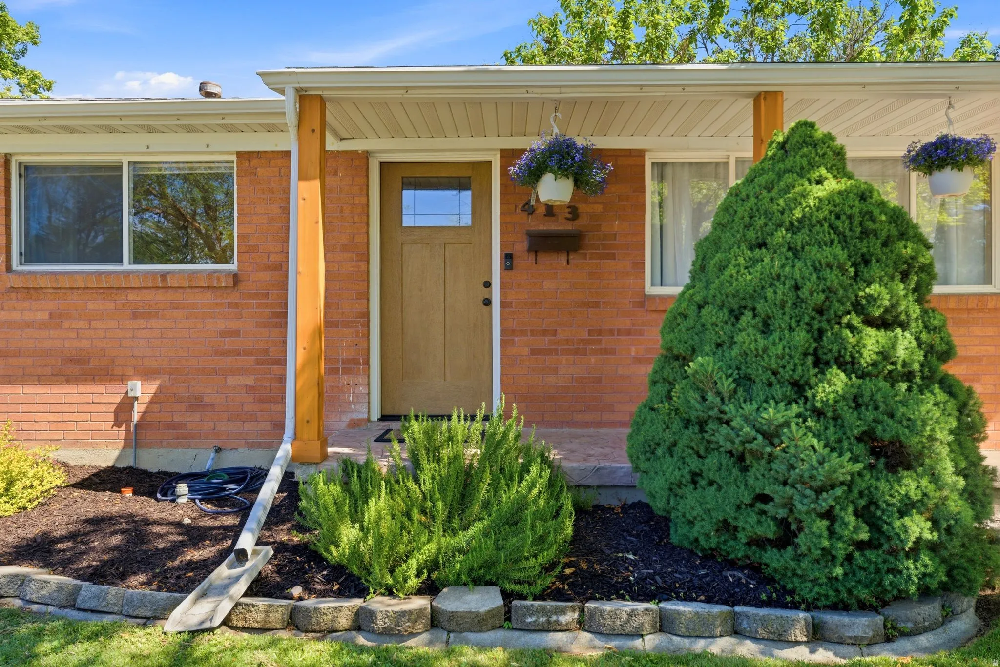 Brick facade with a light wood-finish entry door featuring a glass insert