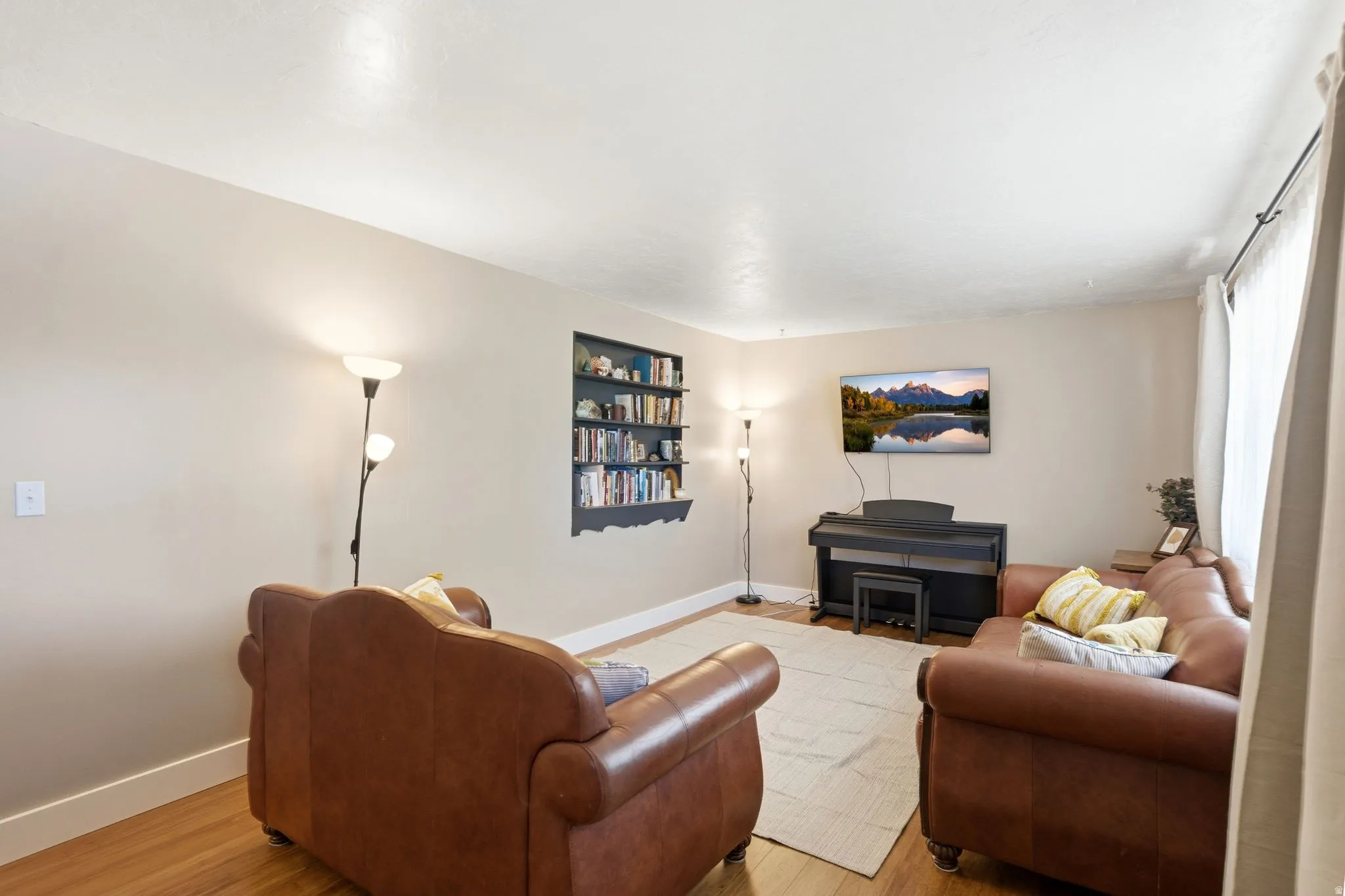 Living area featuring wood-finish flooring, a built-in bookshelf, and light-colored walls