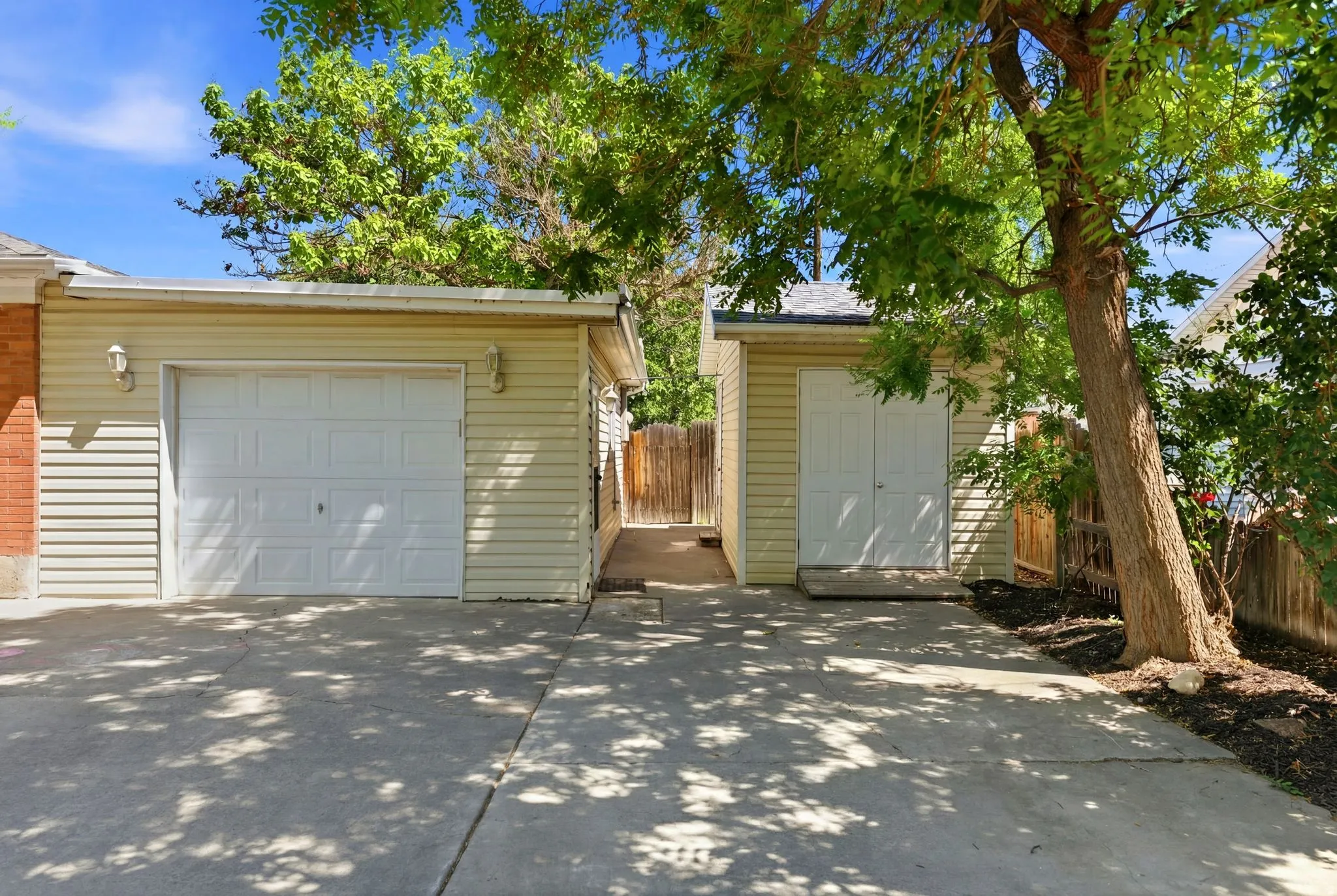 Concrete driveway leading to a single-car garage with an attached storage shed