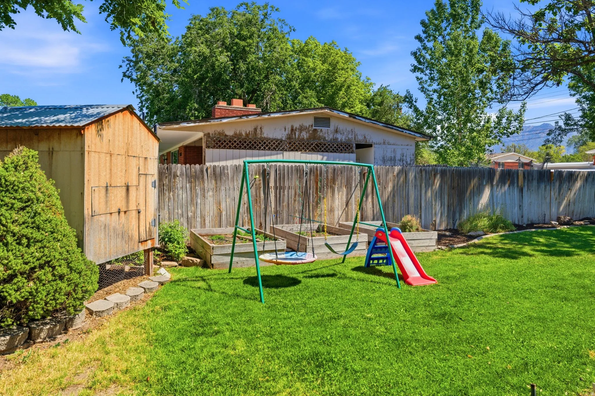 Spacious rear yard with a manicured lawn, established privacy fence, and multiple raised garden beds