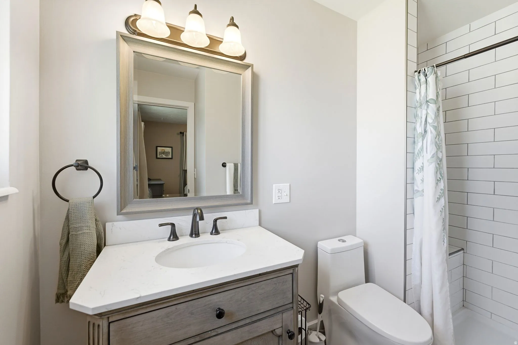 Bathroom vanity featuring a light-toned wood-finish cabinet with a white countertop and oval undermount sink