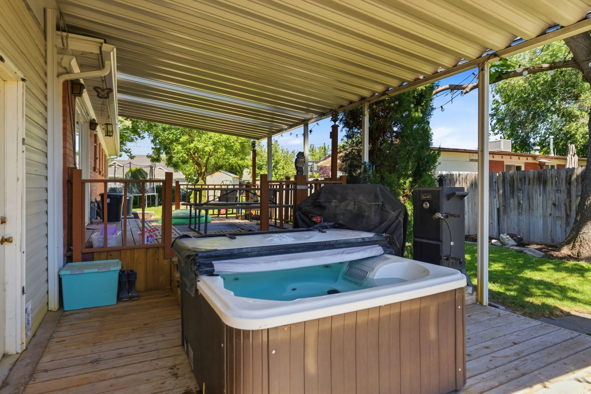 Covered outdoor living space featuring a hot tub and wooden deck
