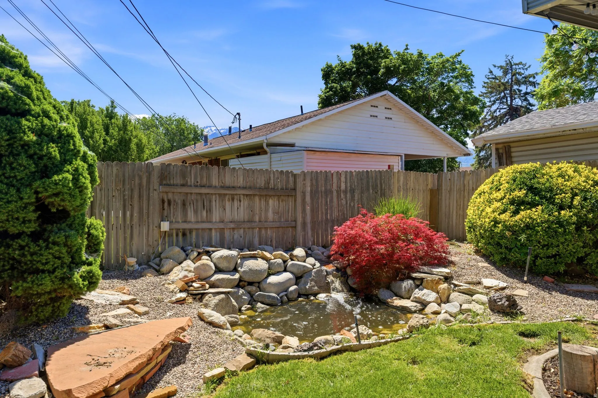 Backyard water feature with stone landscaping and surrounding plantings