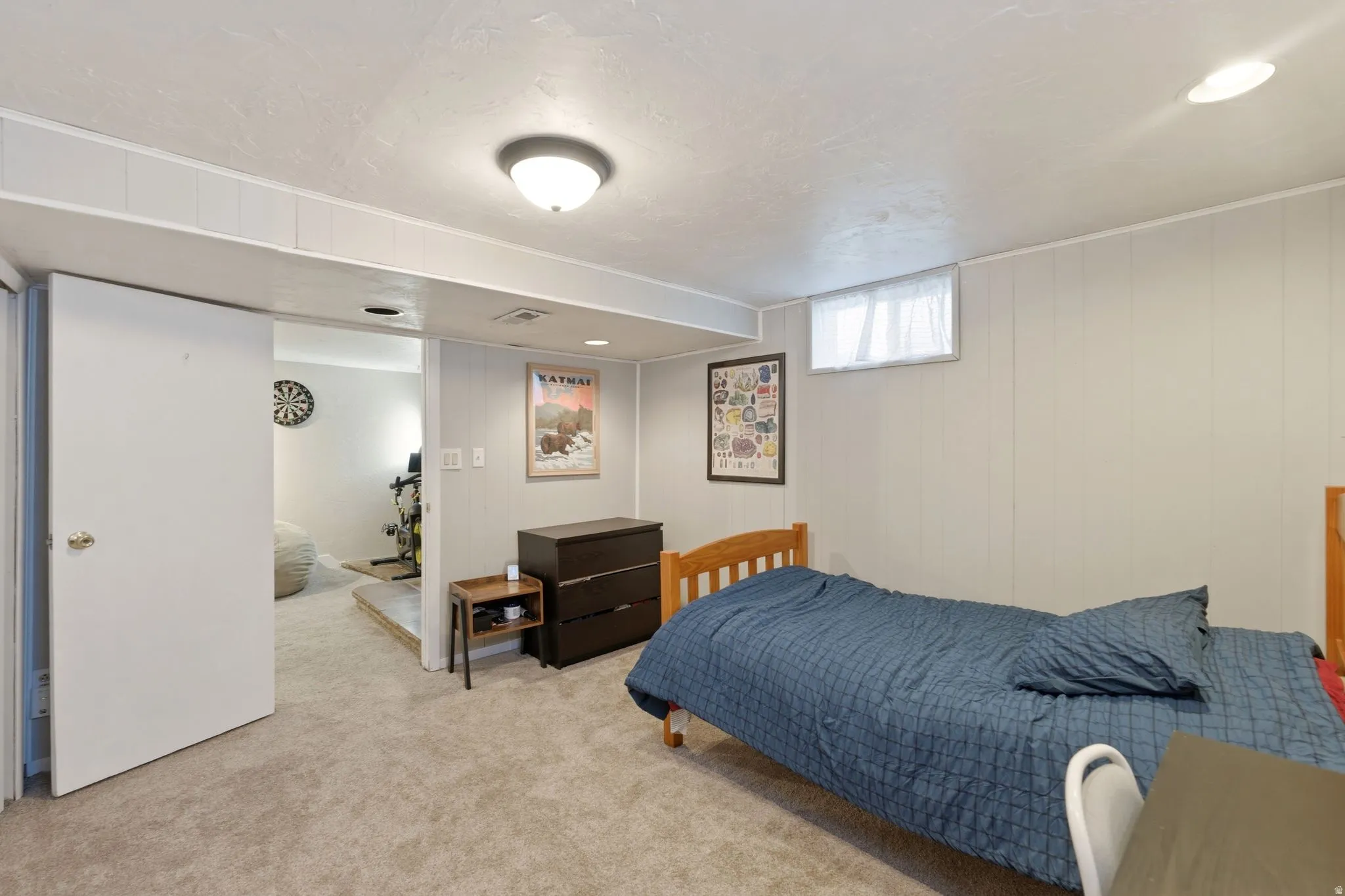 Carpeted room featuring white paneled walls and a window