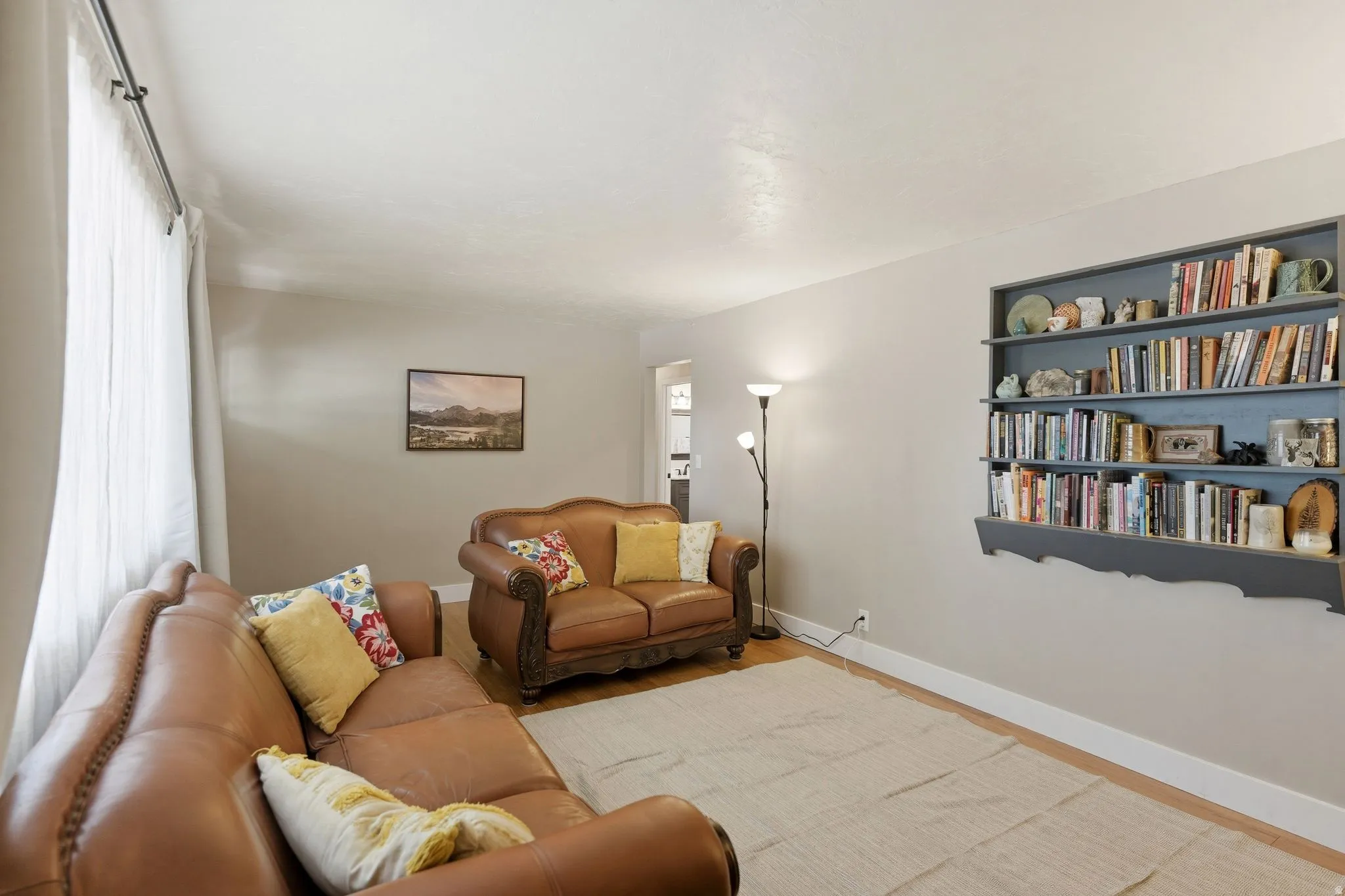 Living area featuring light neutral wall paint, wood-finish flooring, and white baseboards