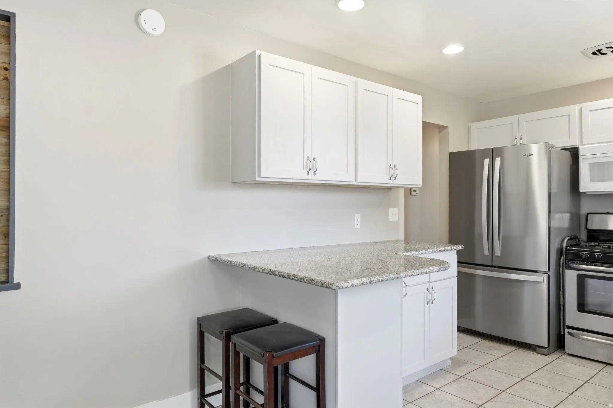 Kitchen featuring white cabinetry, light-toned countertops, stainless steel appliances, and tiled flooring
