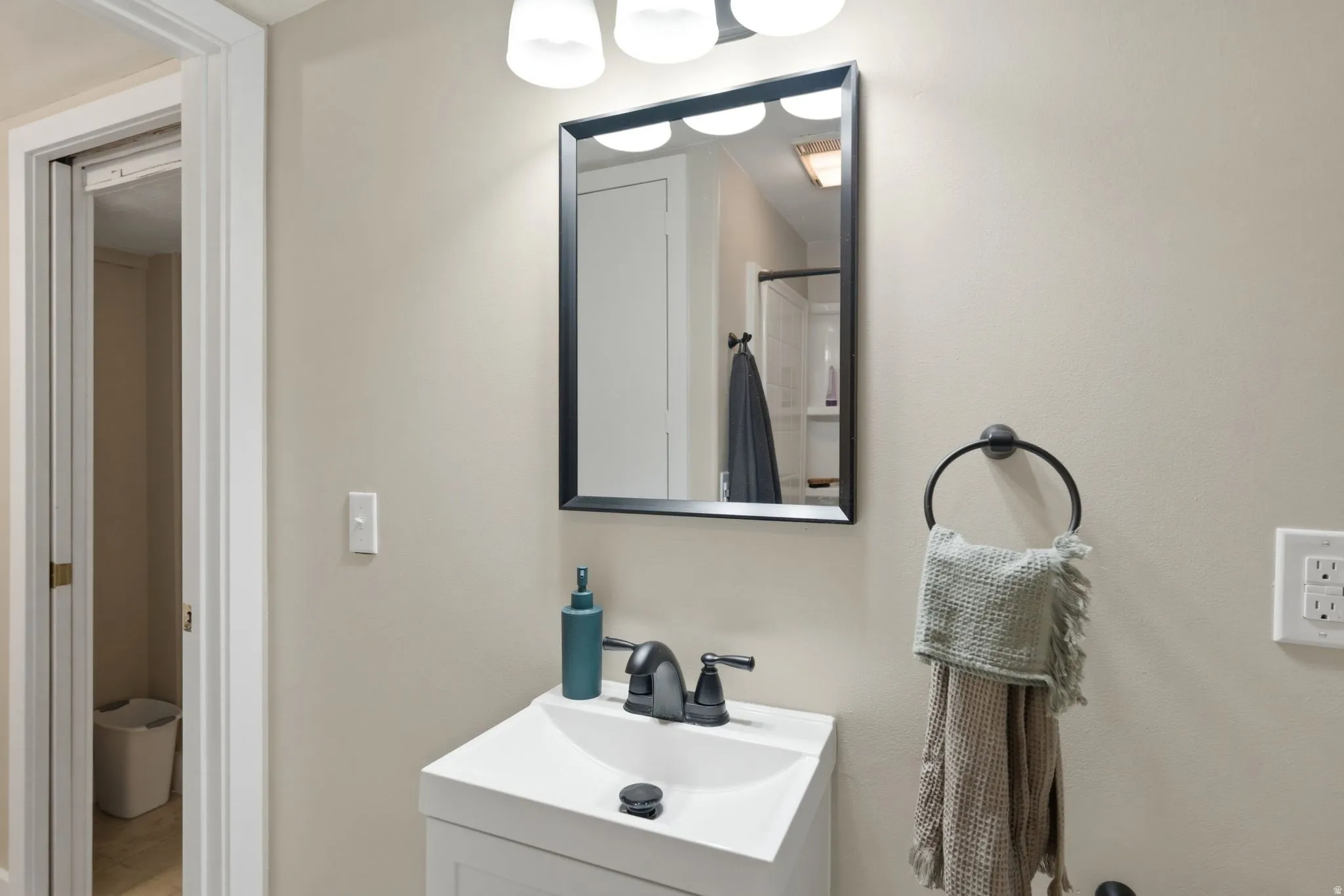 Bathroom vanity featuring a white sink, matte black faucet, and a rectangular mirror with a black frame