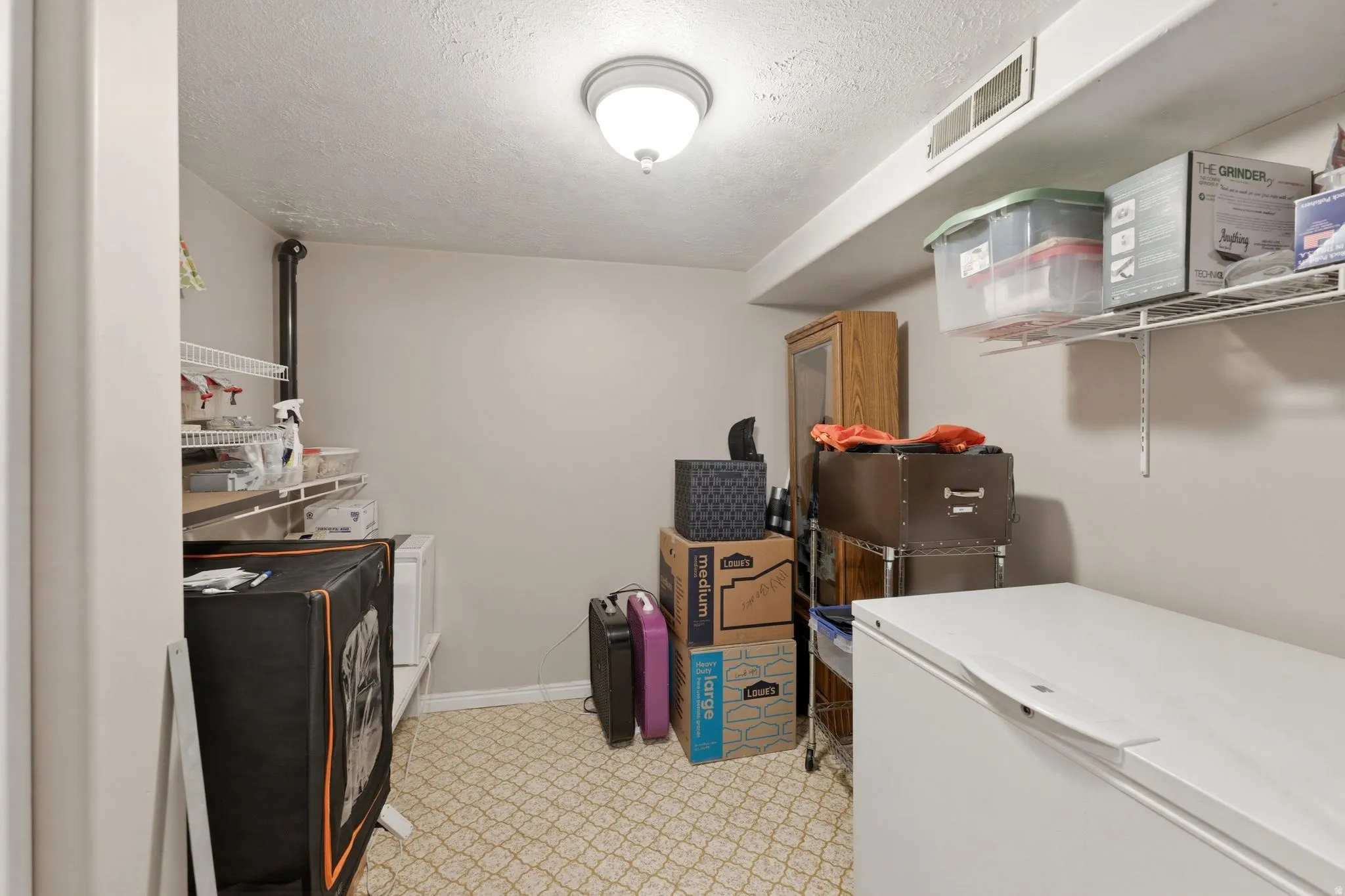 Utility room with wire shelving, textured ceiling, and patterned flooring