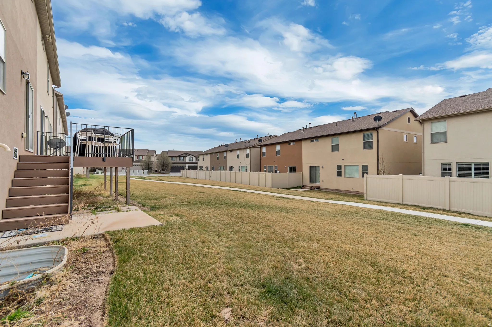 Expansive rear yard featuring a raised deck with metal railings and exterior staircase