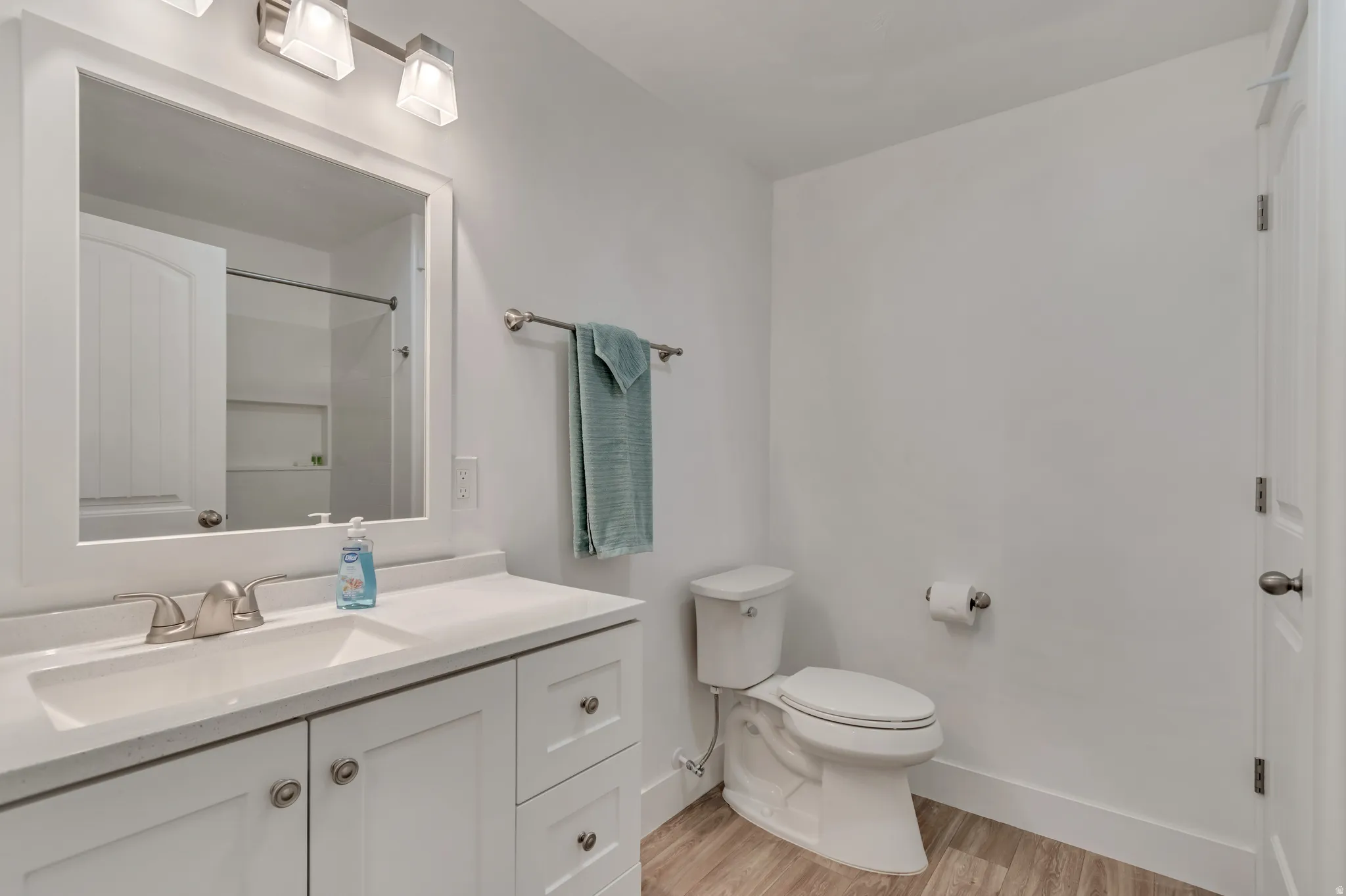 Bathroom featuring a white vanity with an integrated sink, brushed nickel faucet, and overhead bar lighting