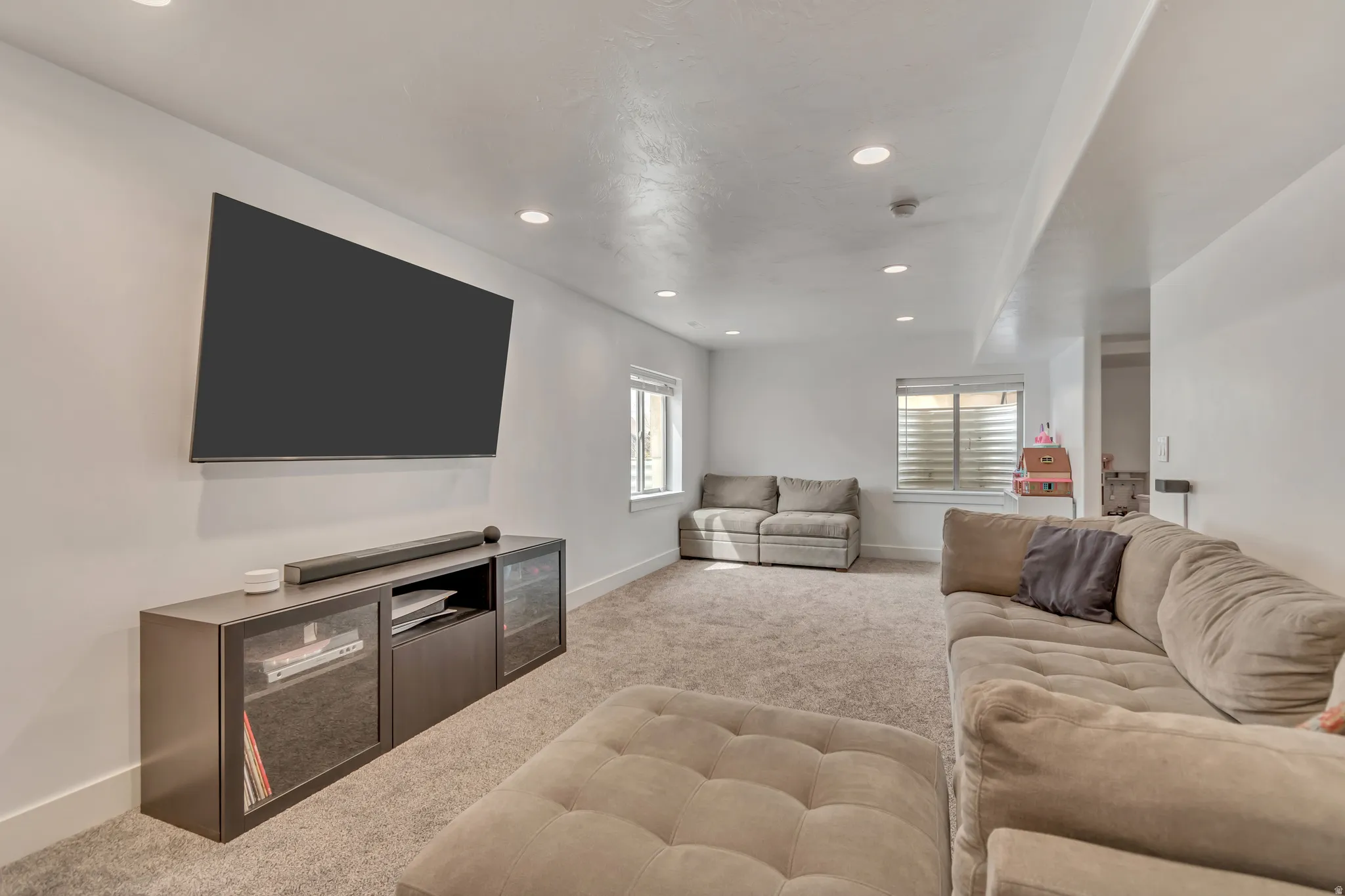 Open concept entertainment area featuring recessed lighting, light-toned carpeting, and multiple windows