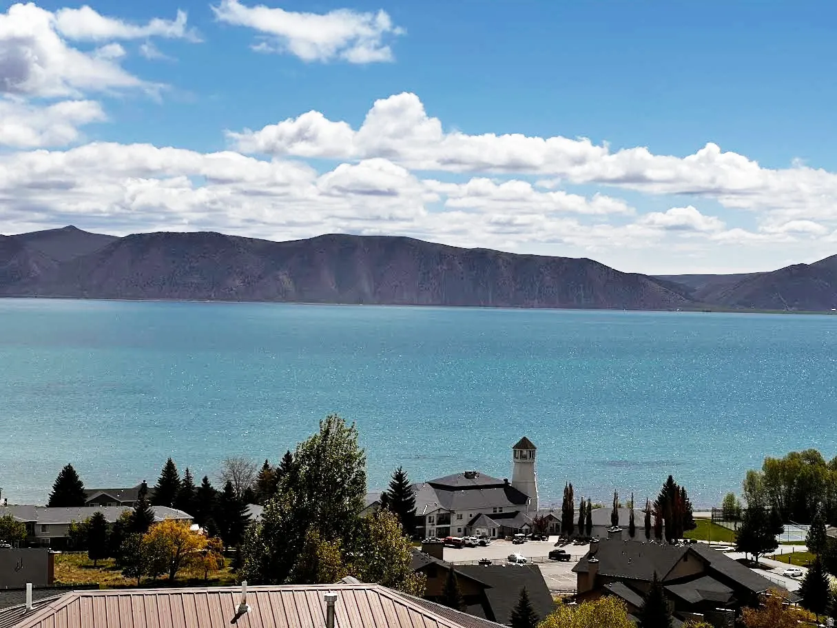 Expansive turquoise lake with distant mountains and a blue sky with white clouds
