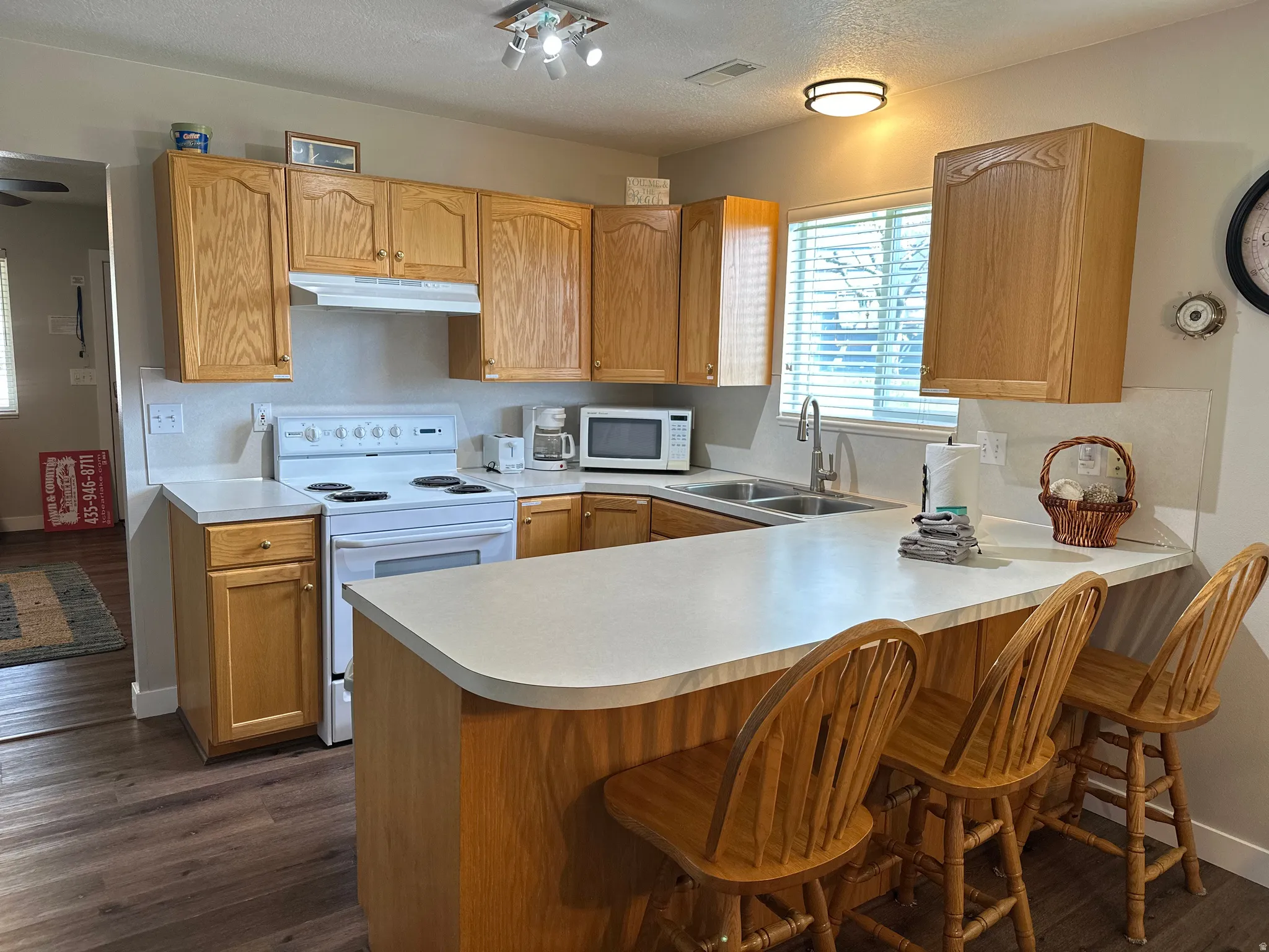 Kitchen featuring light wood cabinetry, white countertops, stainless steel sink with a gooseneck faucet, white appliances, and wood-finish flooring