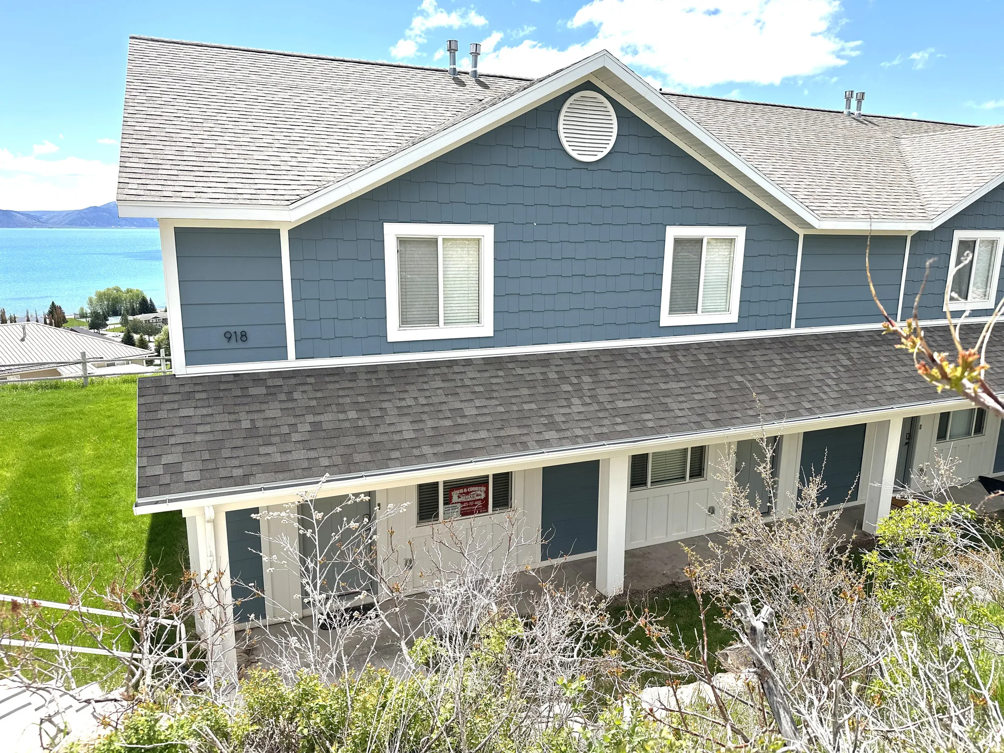 Multi-level exterior featuring blue shingle and lap siding, white trim, and a prominent gable vent