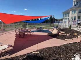 Spacious outdoor patio with red-toned concrete surfacing and overhead shade sails