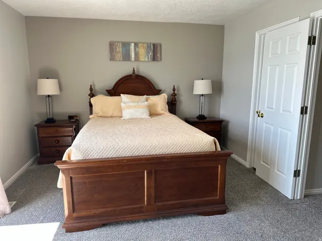 Bedroom featuring neutral wall colors, textured carpet flooring, and a six-panel interior door