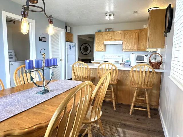 Kitchen and dining area featuring wood-finish flooring, light wood cabinetry, white countertops, and a breakfast bar with seating