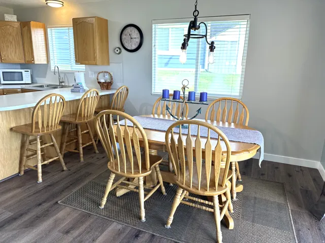 Open-concept kitchen and dining area featuring wood-finish flooring, light wood cabinetry, white countertops, and a built-in breakfast bar