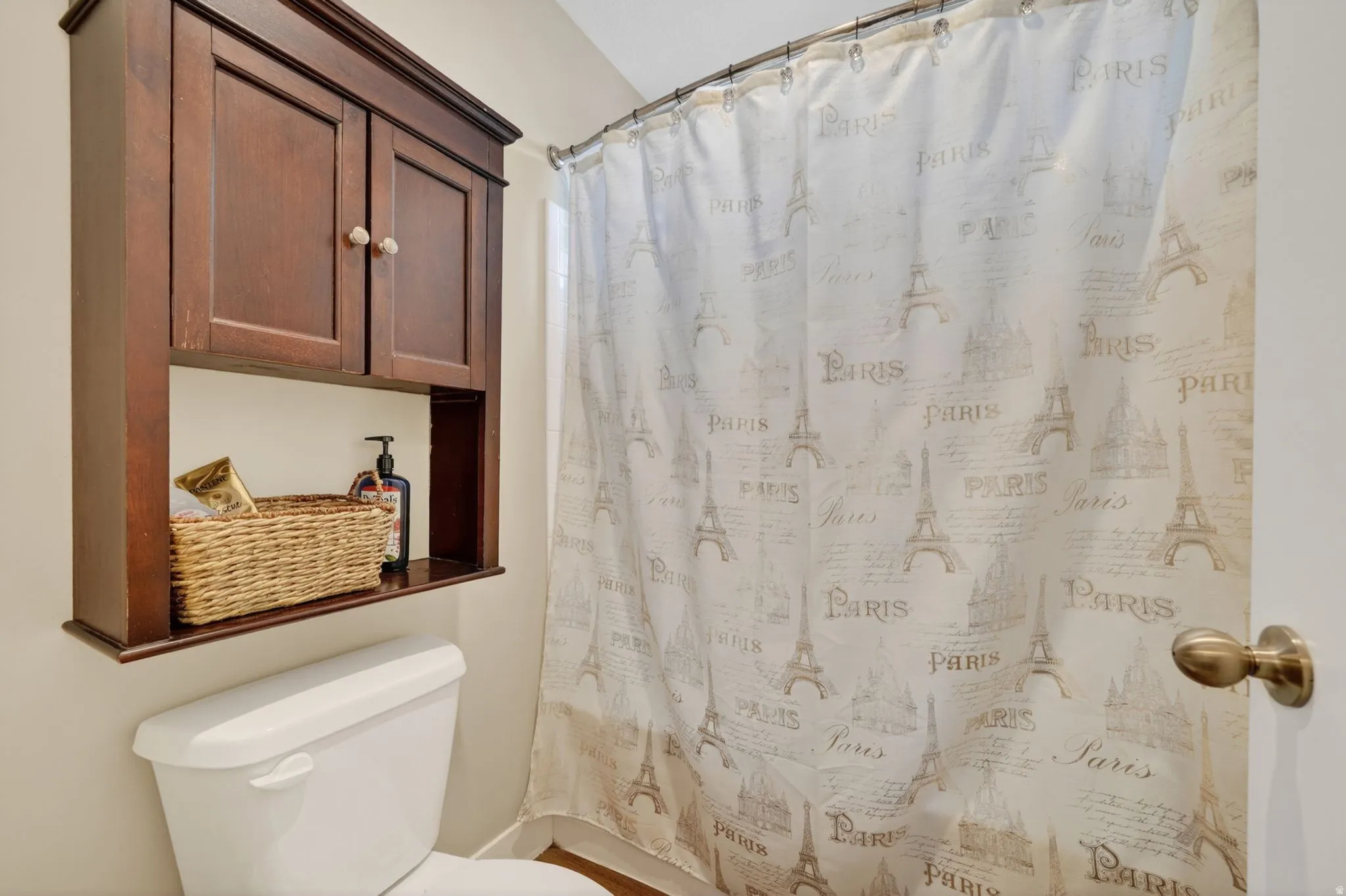 Wall-mounted dark wood cabinetry with open shelving over a white toilet