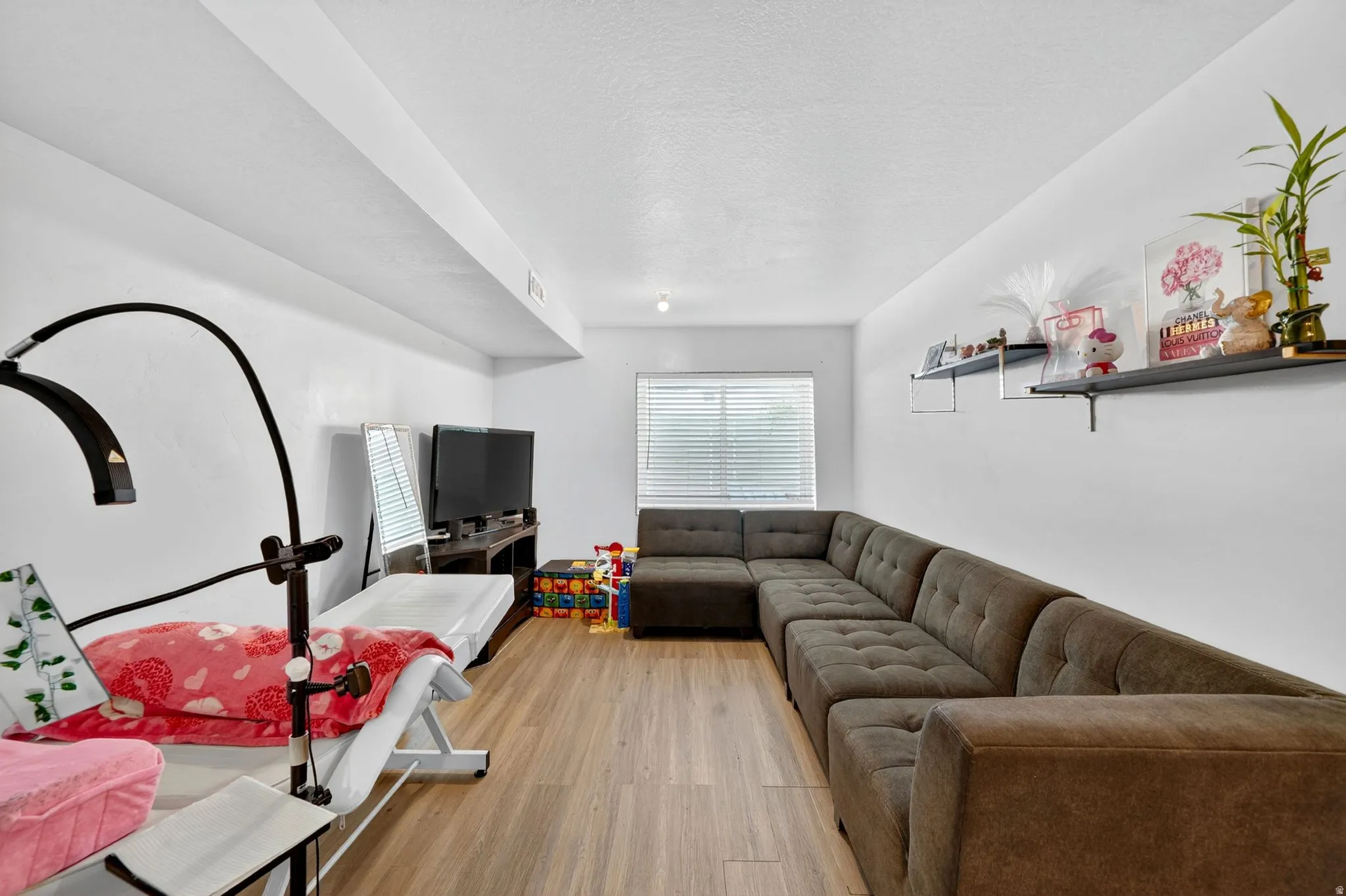 Spacious room featuring wood-finish flooring, white walls, and a recessed ceiling light