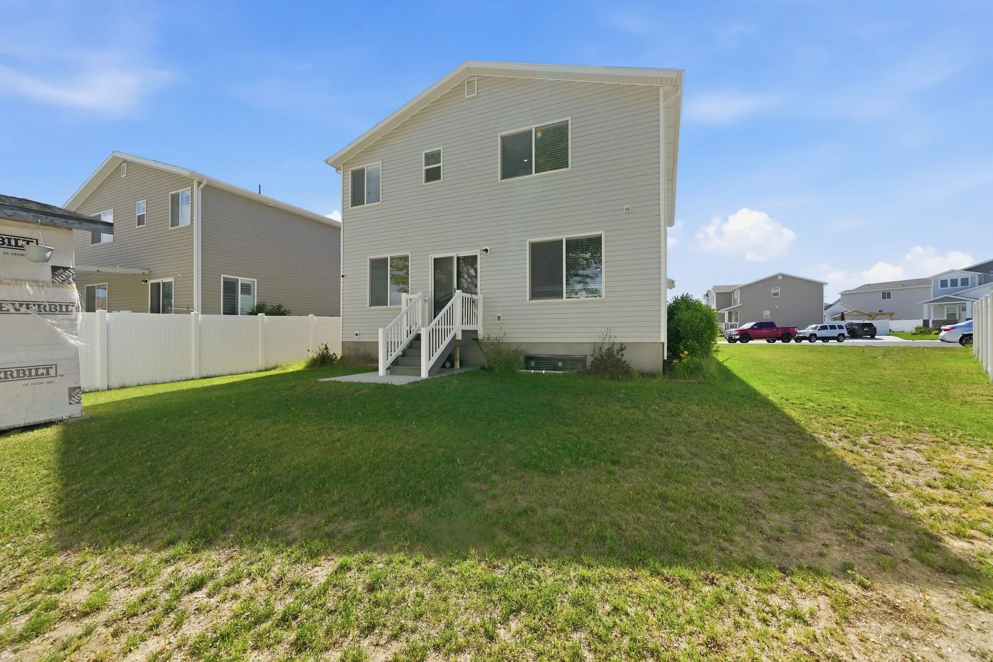 Two-story residence with light-colored siding and a white trim, featuring a ground-level patio and white staircase leading to a second-story door