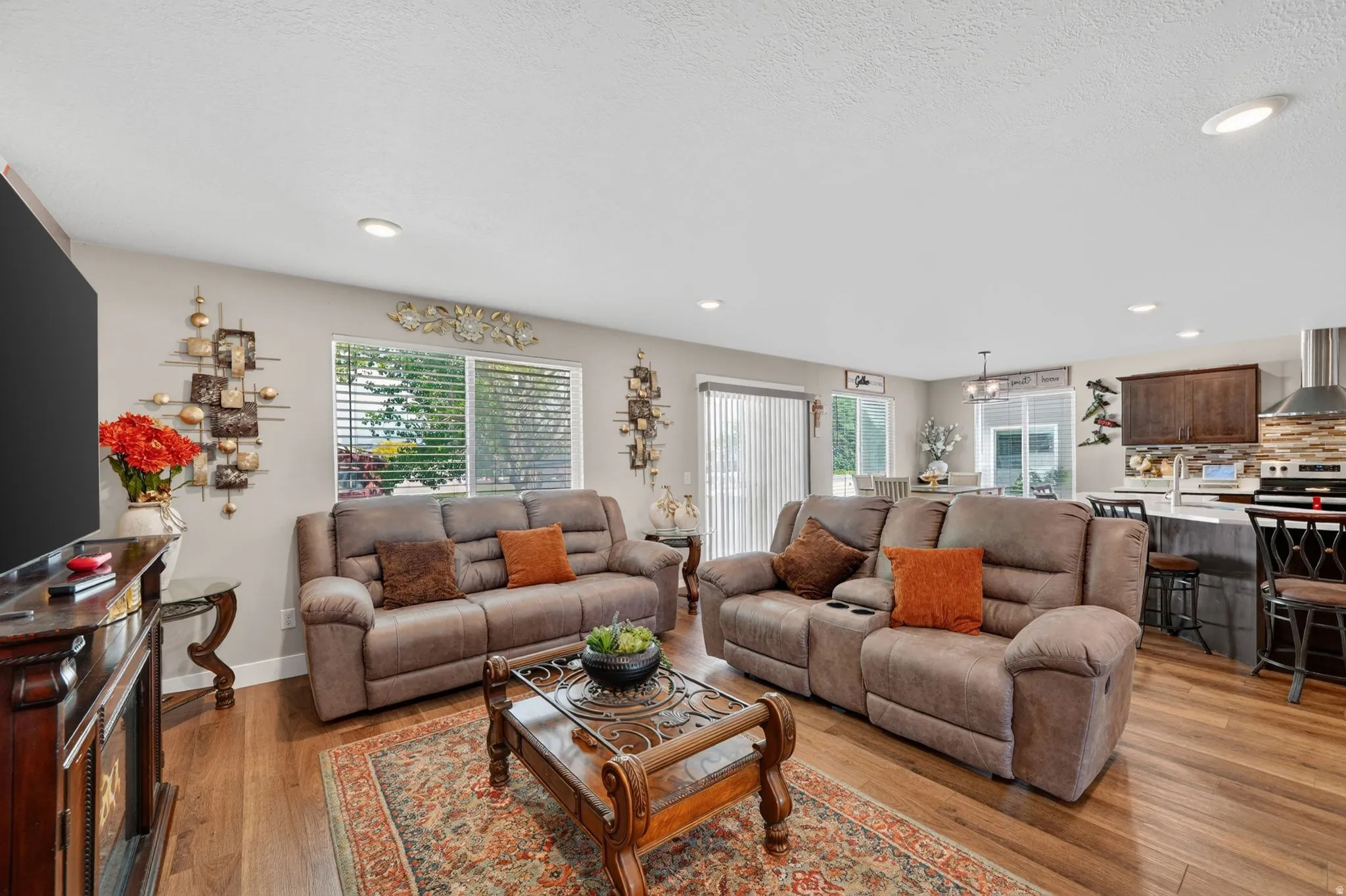 Open-concept living area featuring wood-finish flooring, recessed lighting, and ample natural light from multiple windows