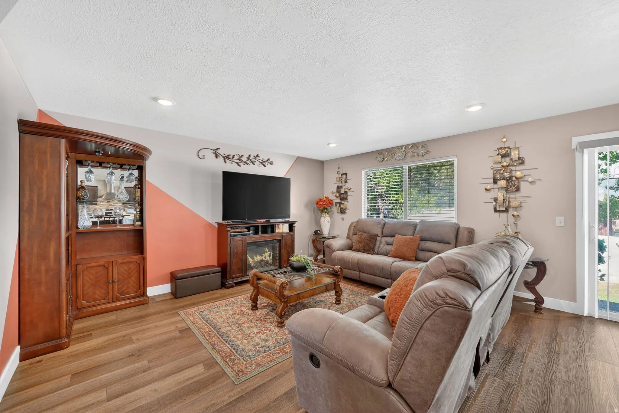 Spacious living area featuring wood-finish flooring, recessed lighting, and a built-in electric fireplace