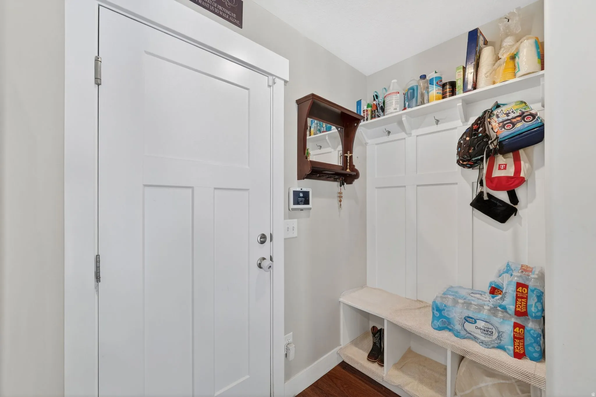 Entryway featuring a white paneled door, built-in mudroom bench with storage, upper shelving, and wall-mounted coat hooks