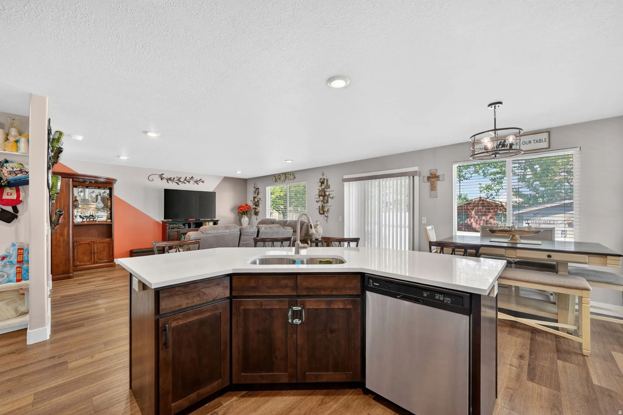 Kitchen island featuring a stainless steel dishwasher, undermount sink, and light-toned countertops
