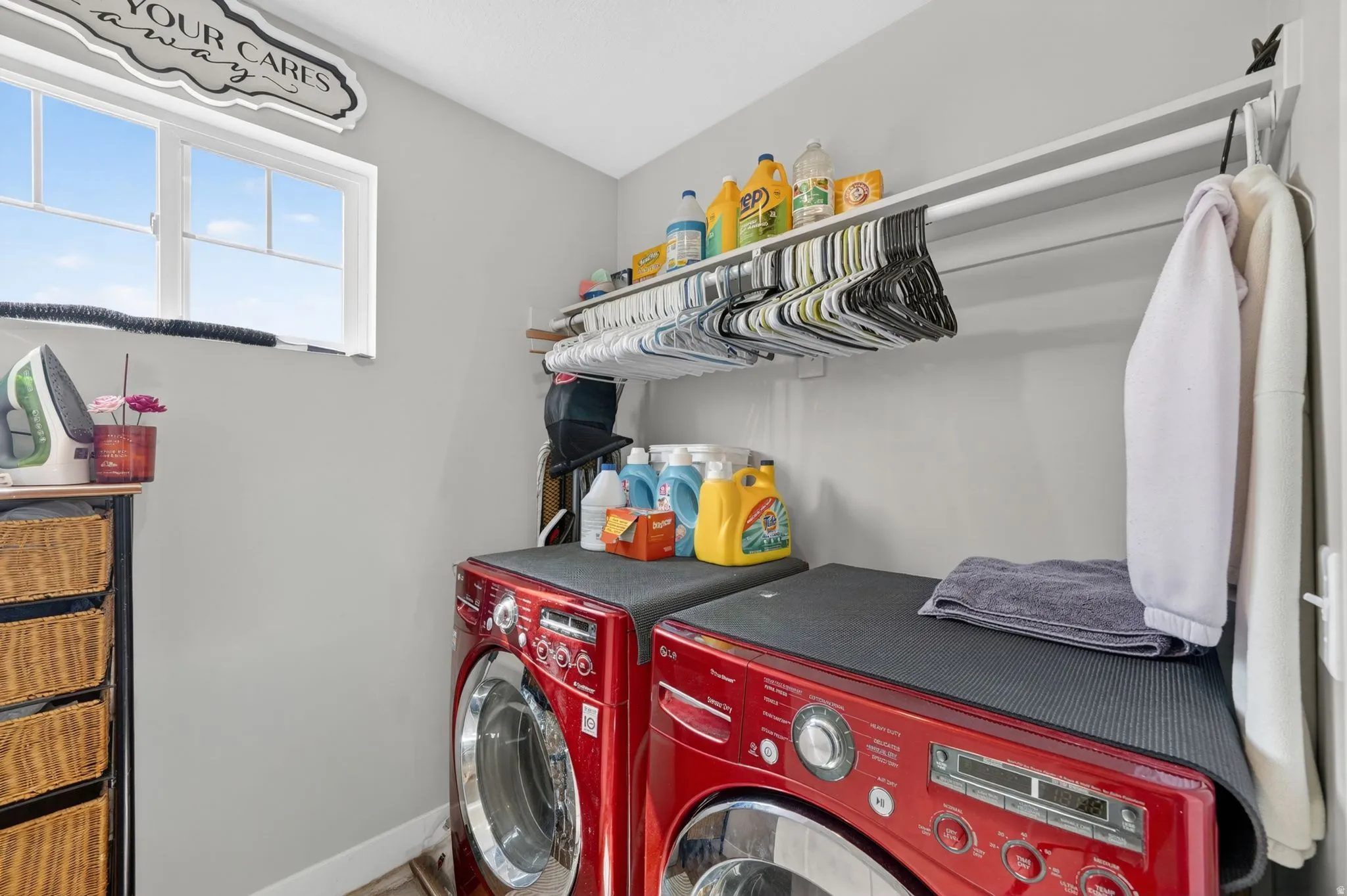 Dedicated laundry space featuring a window, built-in shelving, a clothes hanging rod, and two red front-loading appliances