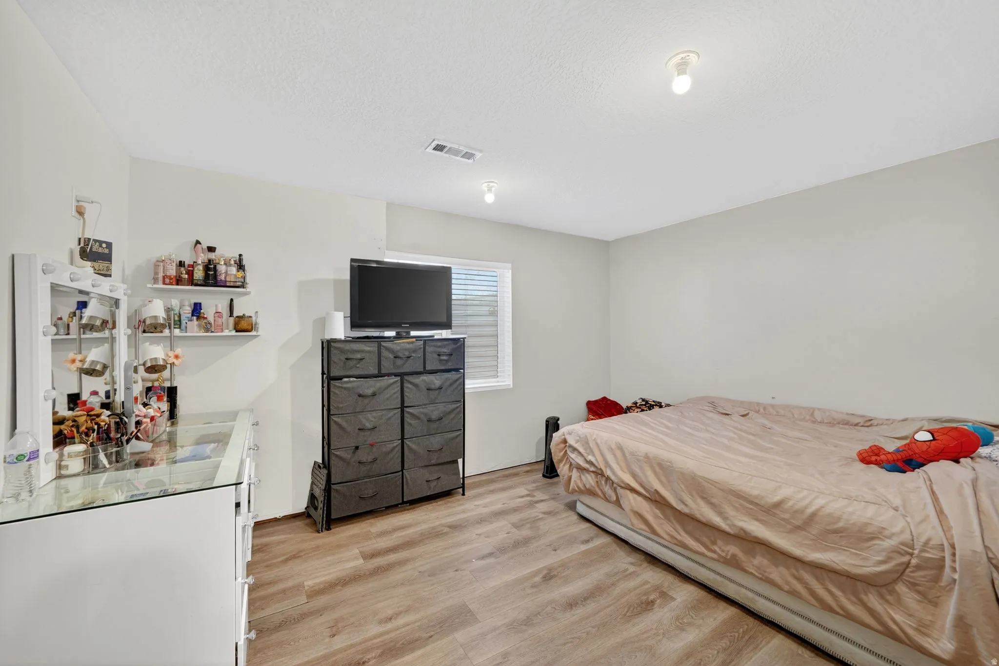 Neutral wall paint, wood-finish flooring, and a single window with blinds