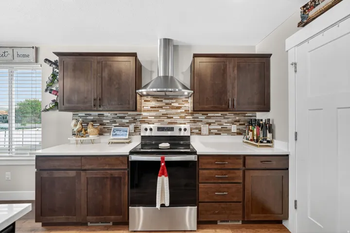 Contemporary kitchen featuring dark wood cabinetry, white countertops, and a tiled backsplash
