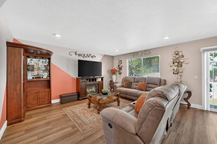 Spacious living area featuring wood-finish flooring, recessed lighting, and a built-in electric fireplace