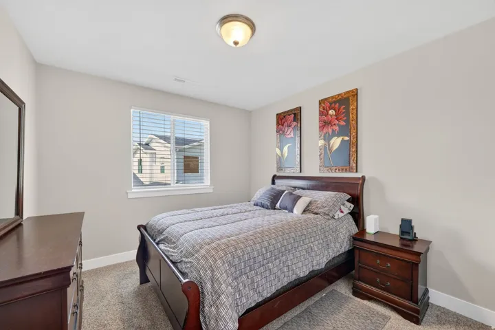 Bedroom featuring neutral-toned walls, a single window with blinds, and carpeted flooring