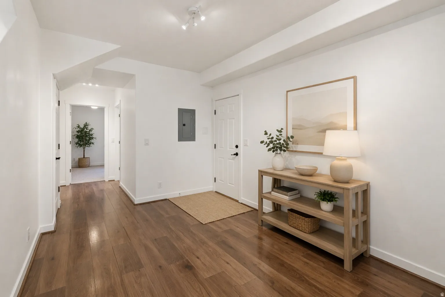 Spacious hallway featuring wood-finish flooring, white walls, recessed ceiling lights, and white trim