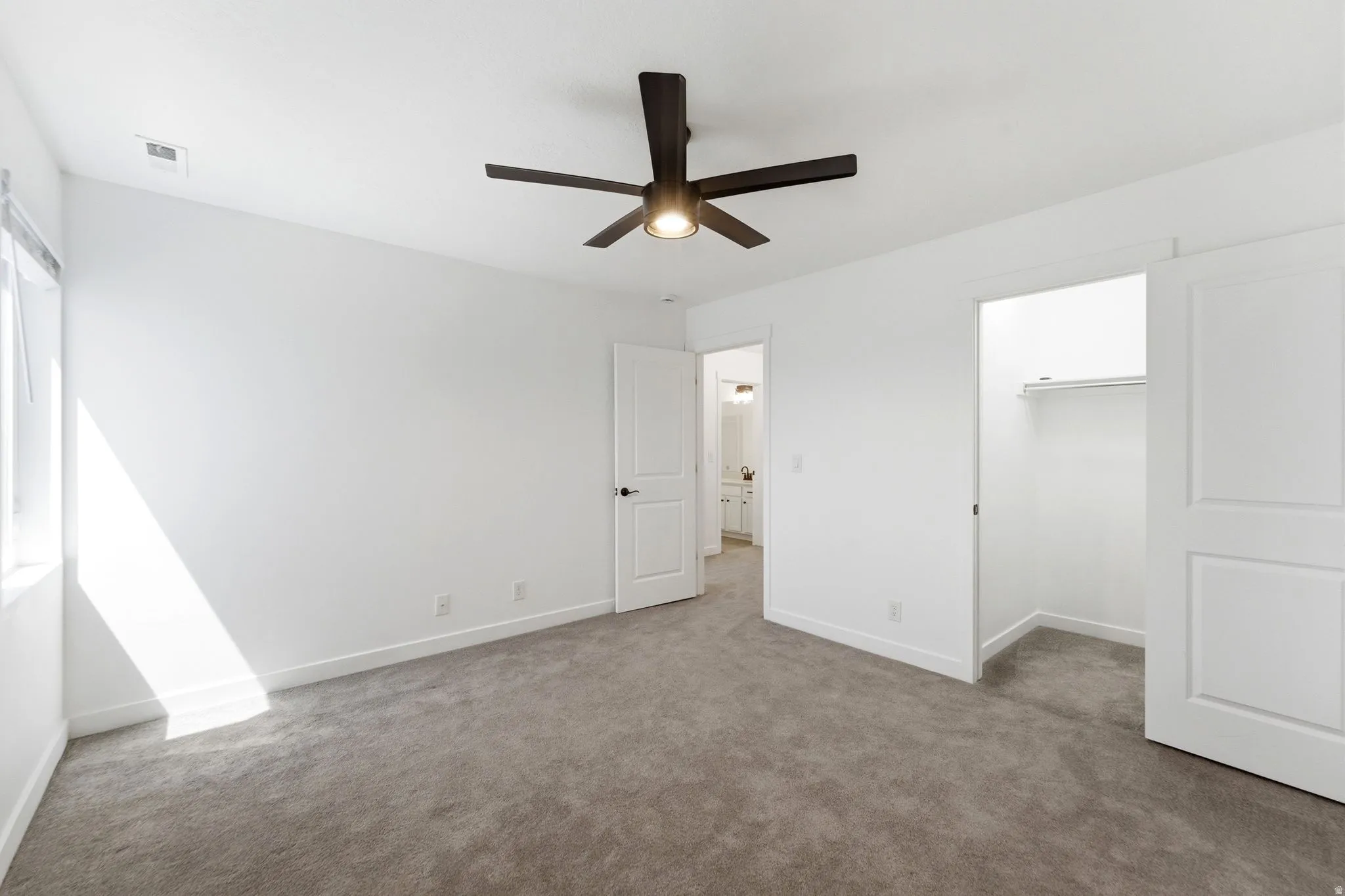 Neutral carpeted room with a modern ceiling fan, white walls, and a window