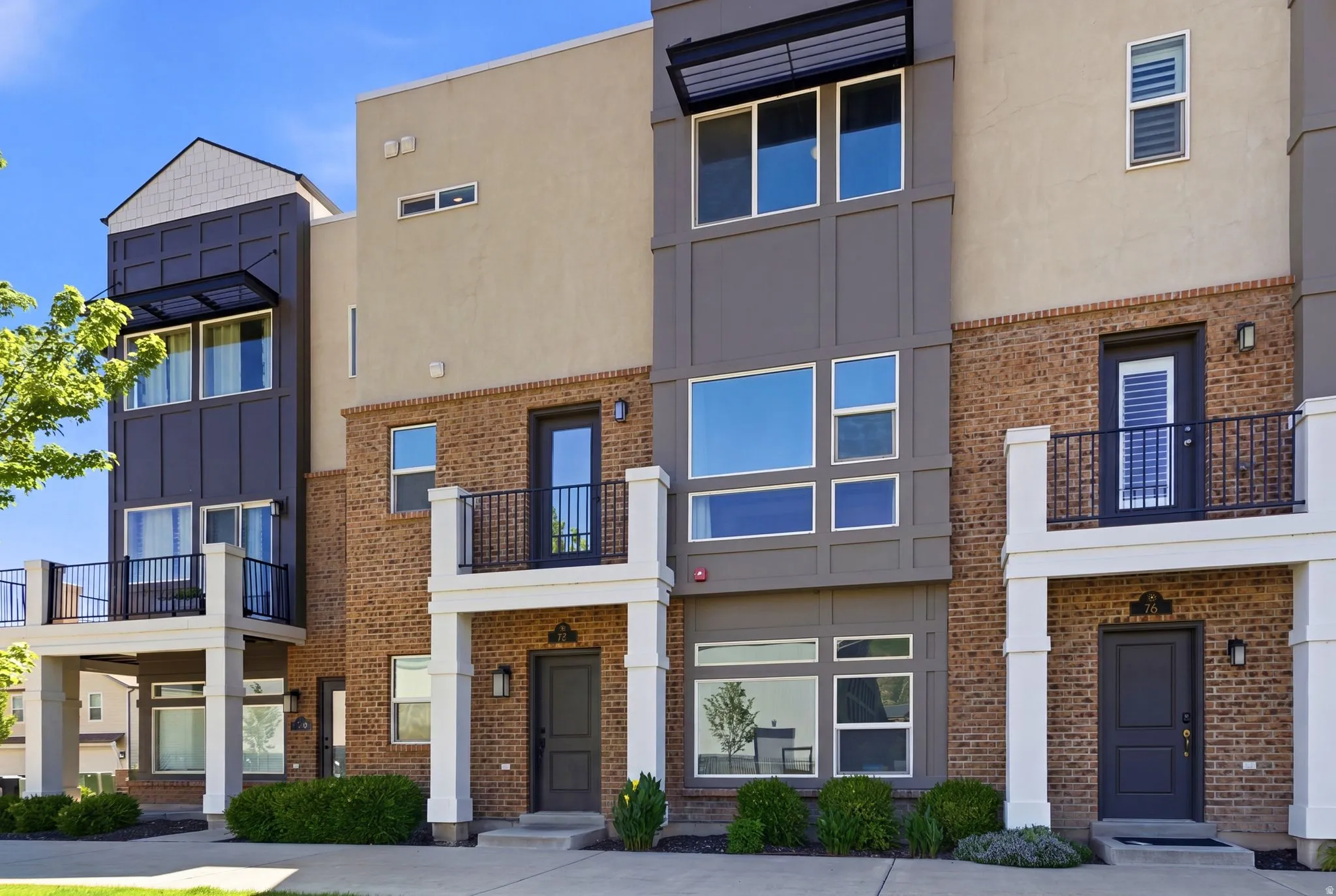 Modern townhome exterior featuring a multi-material facade with brick, stucco, and dark paneling