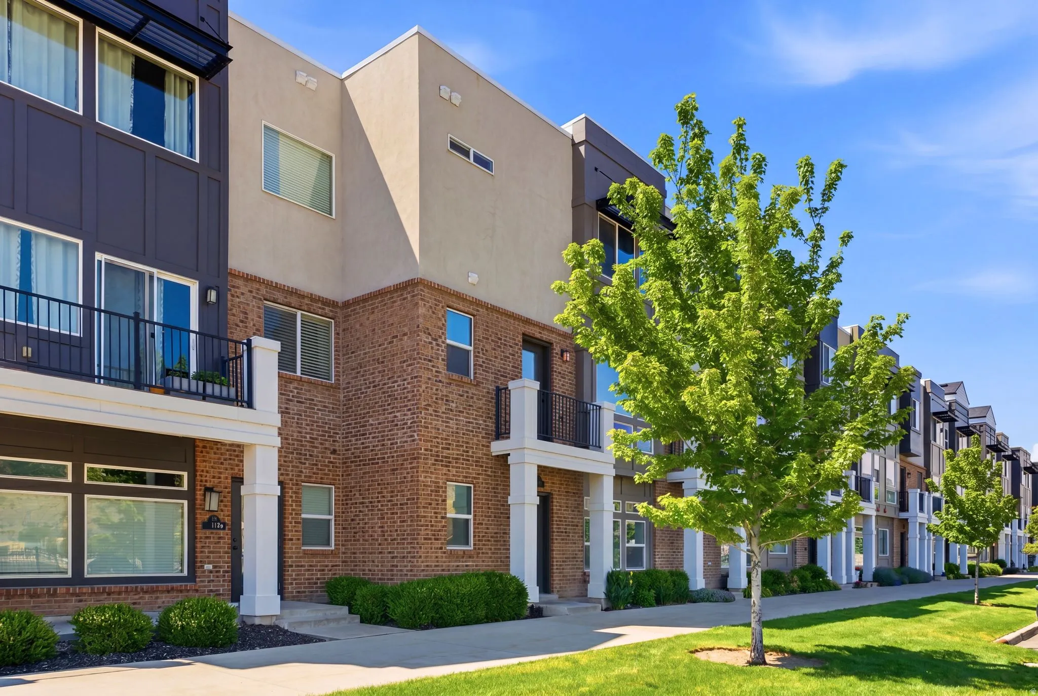 Contemporary townhome facade featuring a blend of brick and stucco materials
