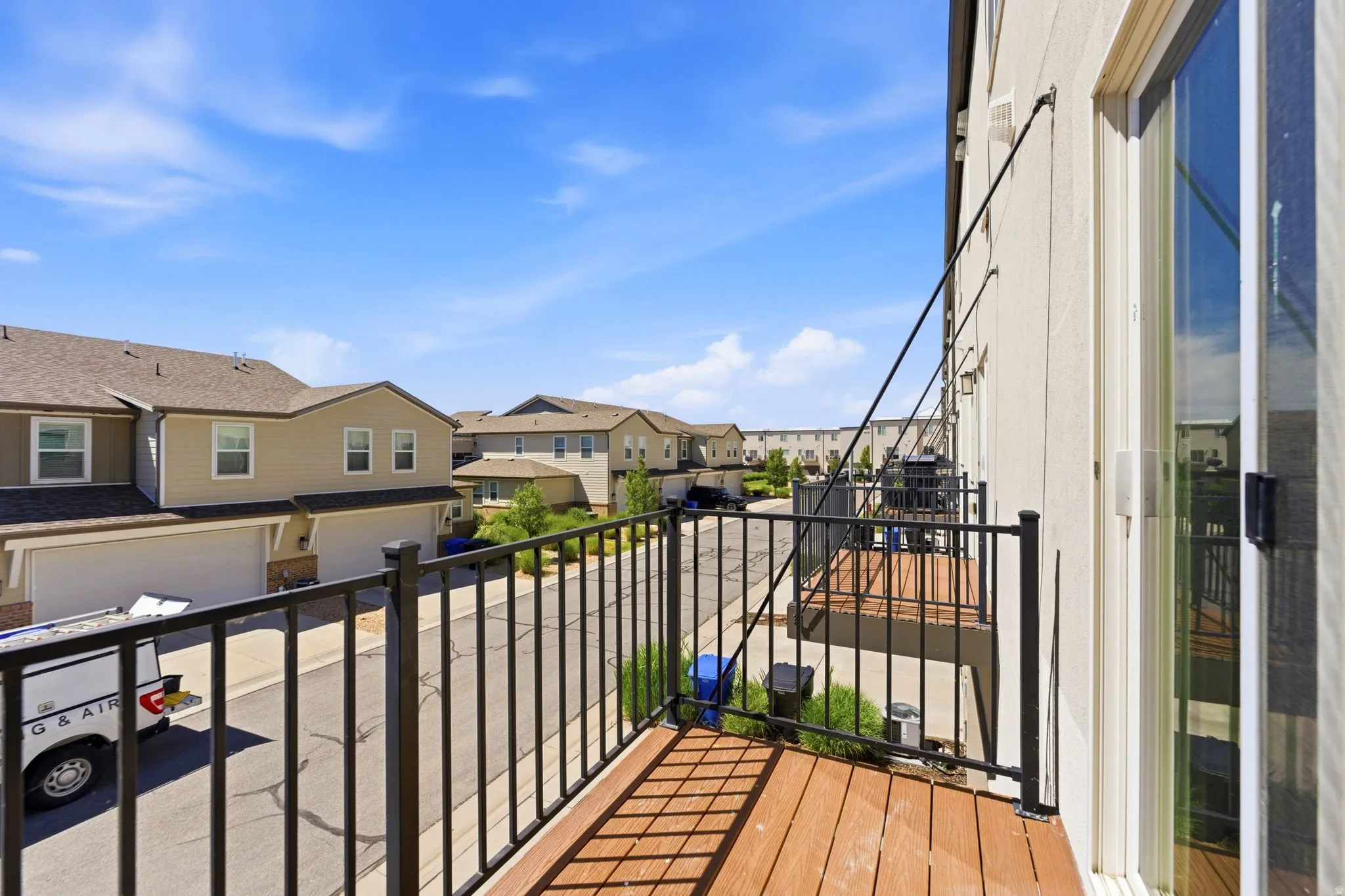 Private outdoor balcony featuring wood-finish decking and black iron railings