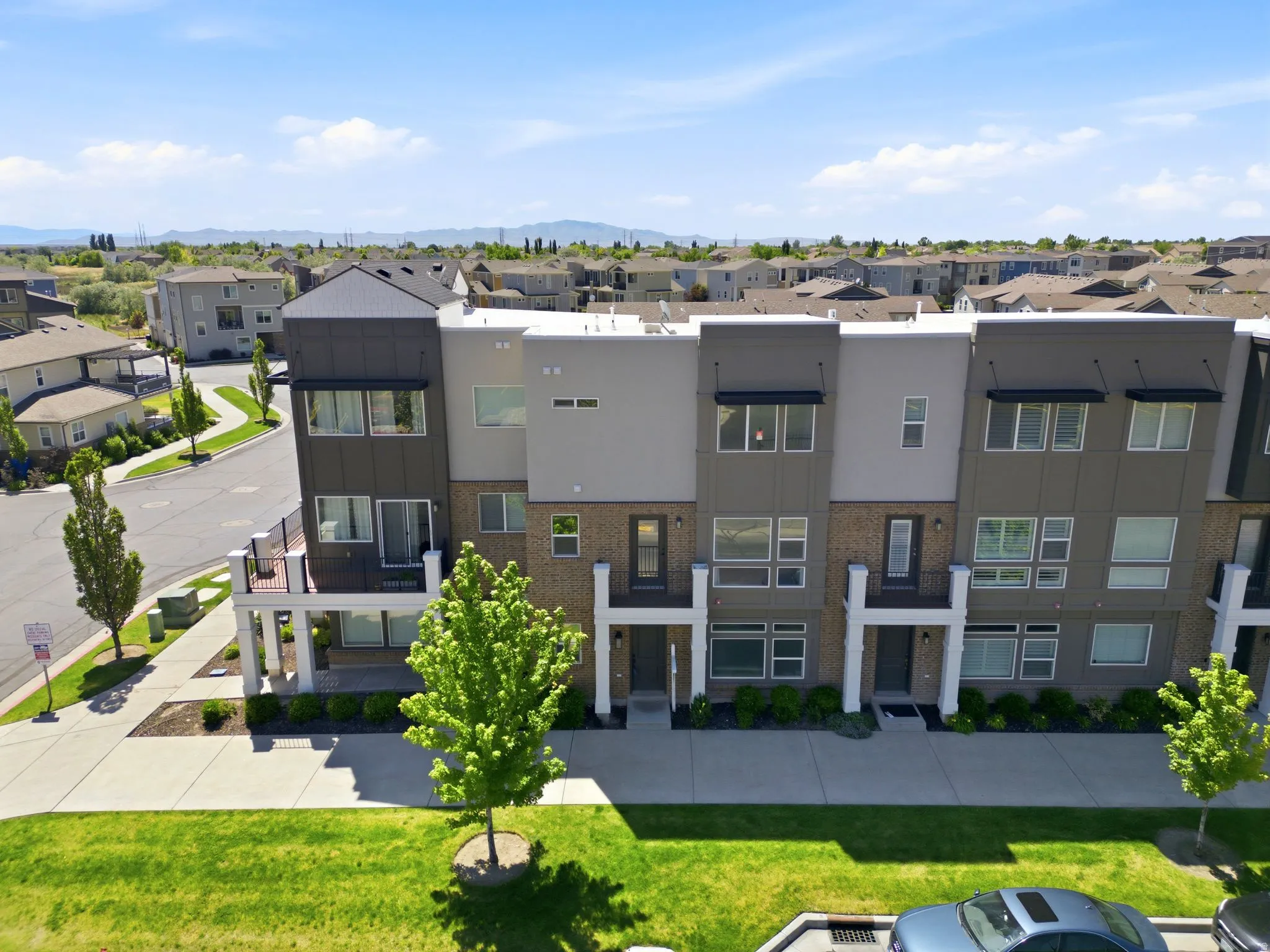 Contemporary multi-level townhome featuring a mixed-material facade with brick, gray siding, and black accents