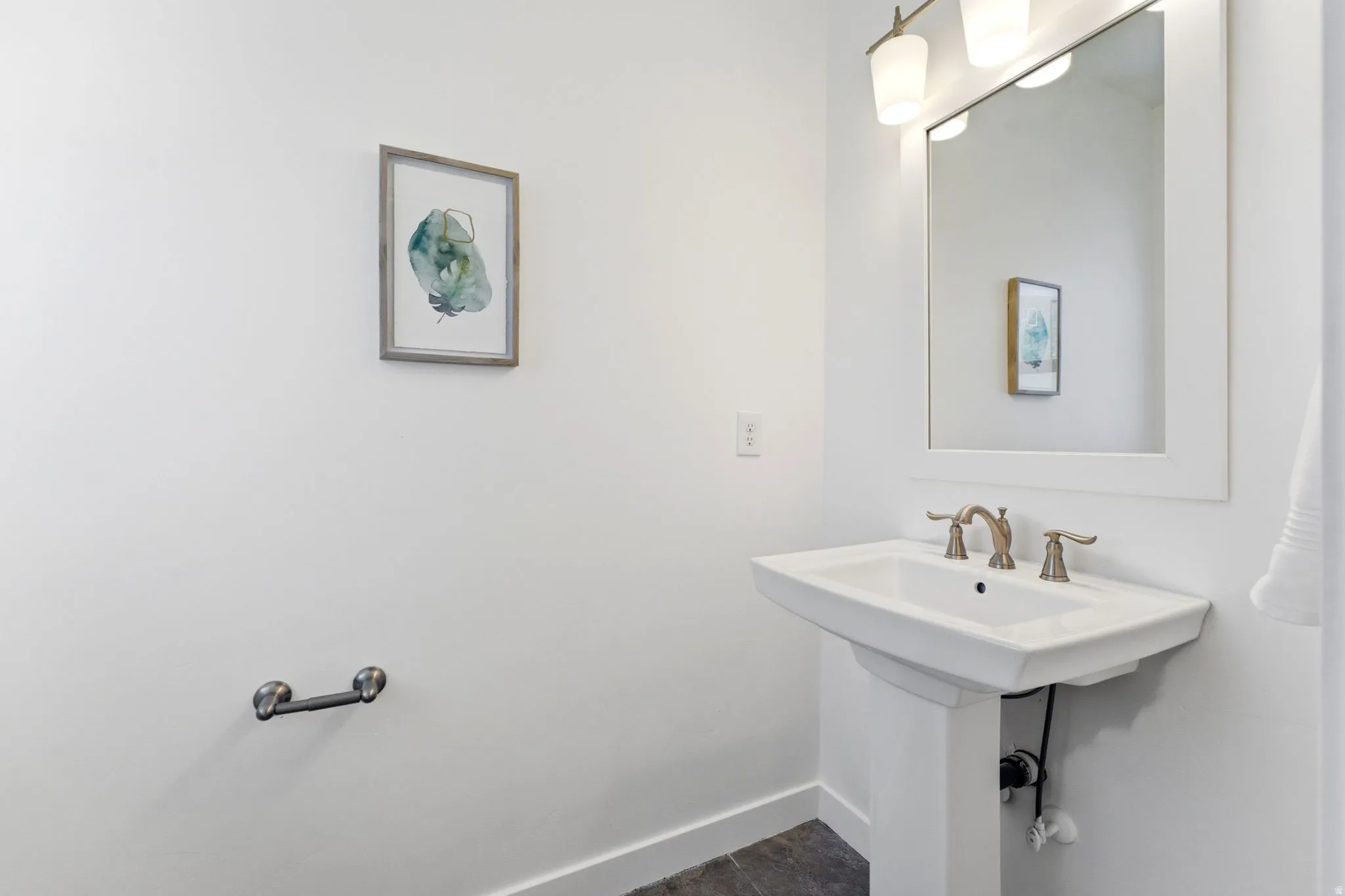 Pedestal sink with bronze-finish faucet, rectangular framed mirror, and two-light vanity fixture