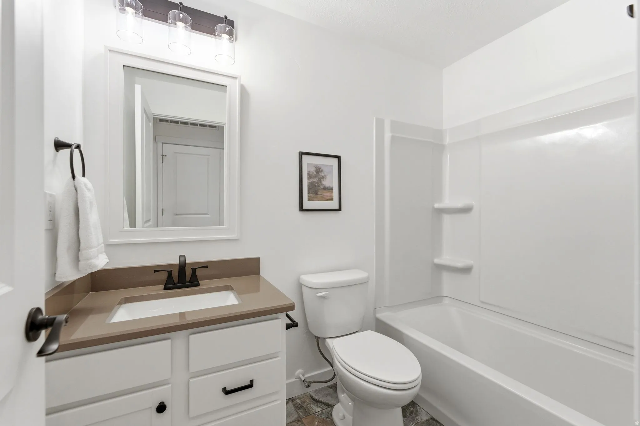 Bright bathroom with white vanity cabinetry, integrated sink, and bronze-finish fixtures