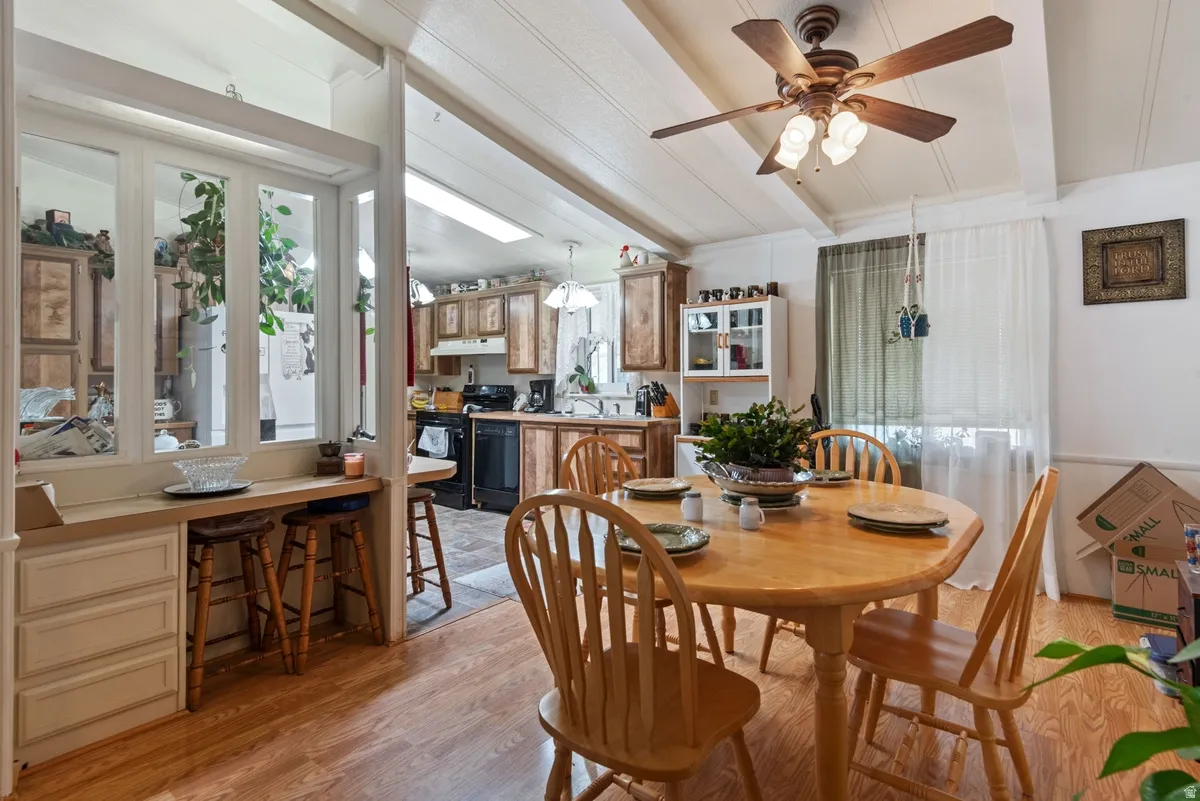 Wood-finish flooring extends throughout this dining area, featuring a decorative ceiling fan and a built-in pass-through with additional cabinetry