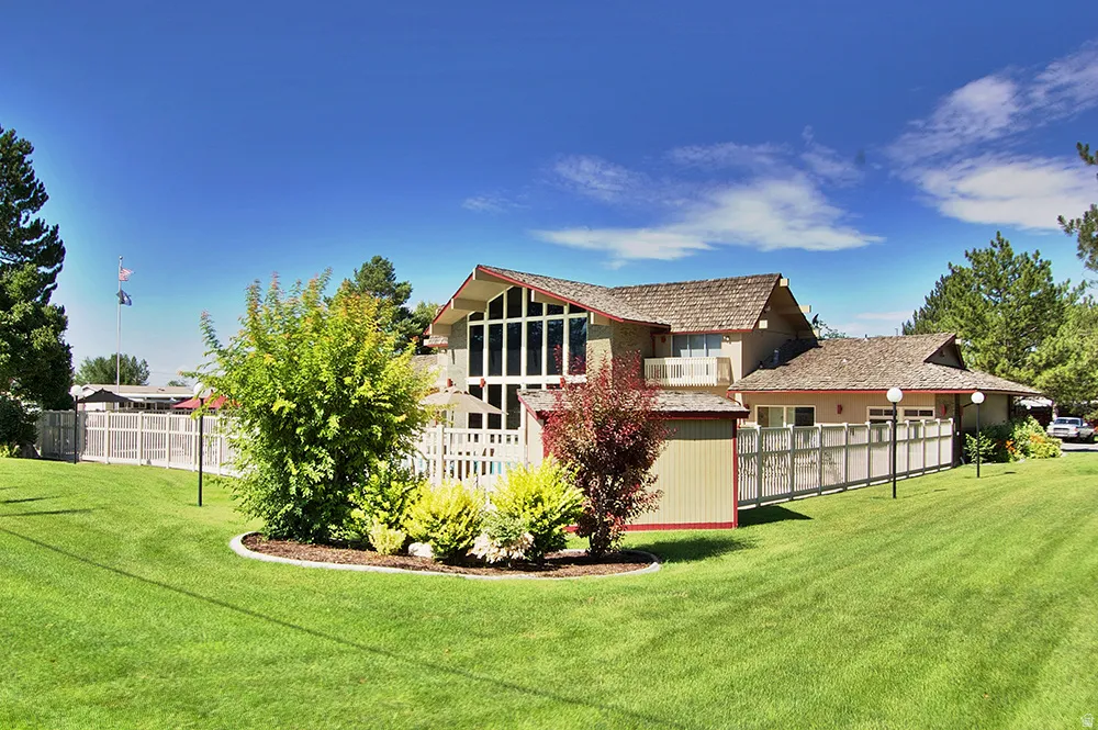 Expansive green lawn surrounds a multi-level property featuring a prominent window wall, a wood shingle roof, and exterior lighting fixtures