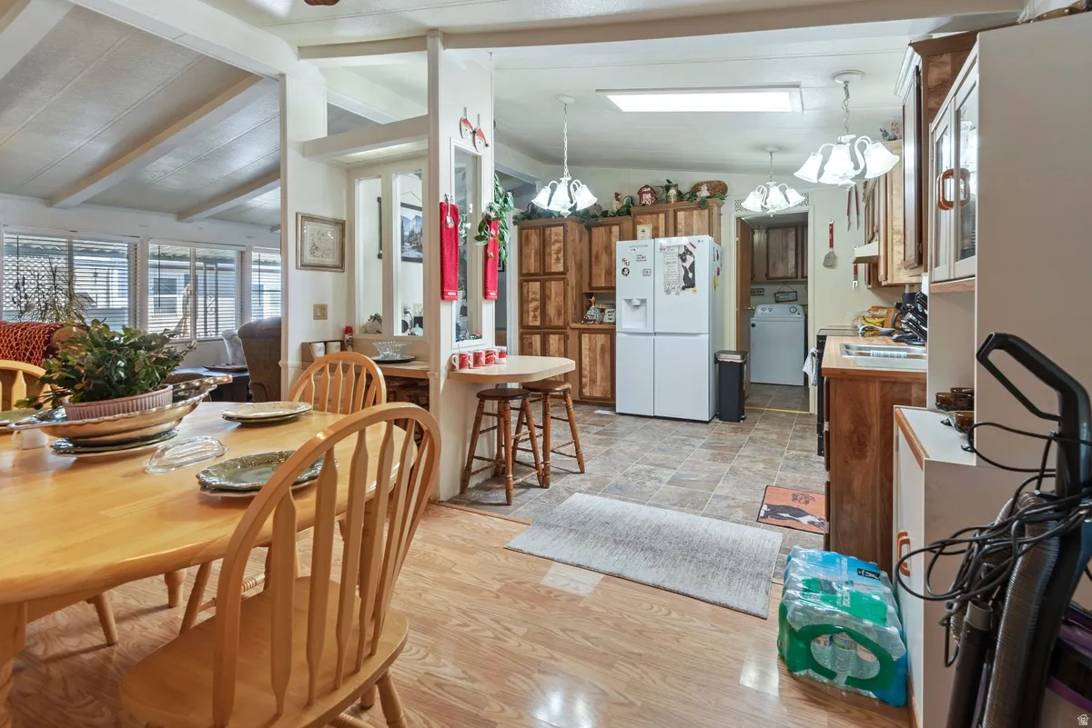 Open-concept dining area featuring wood-finish flooring, a breakfast bar, and vaulted ceilings