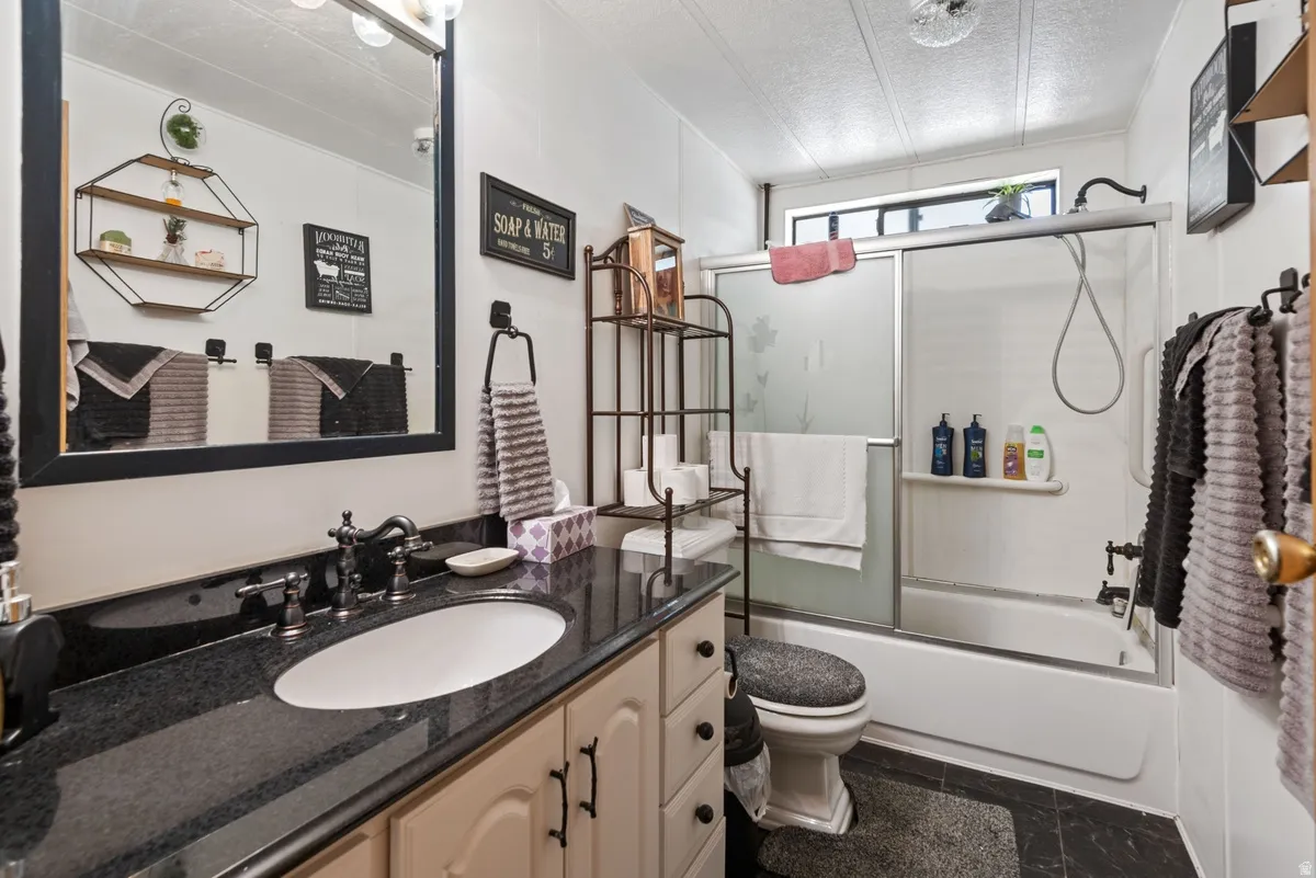 Bathroom featuring a vanity with a dark countertop, an oval undermount sink, and a dark-framed mirror
