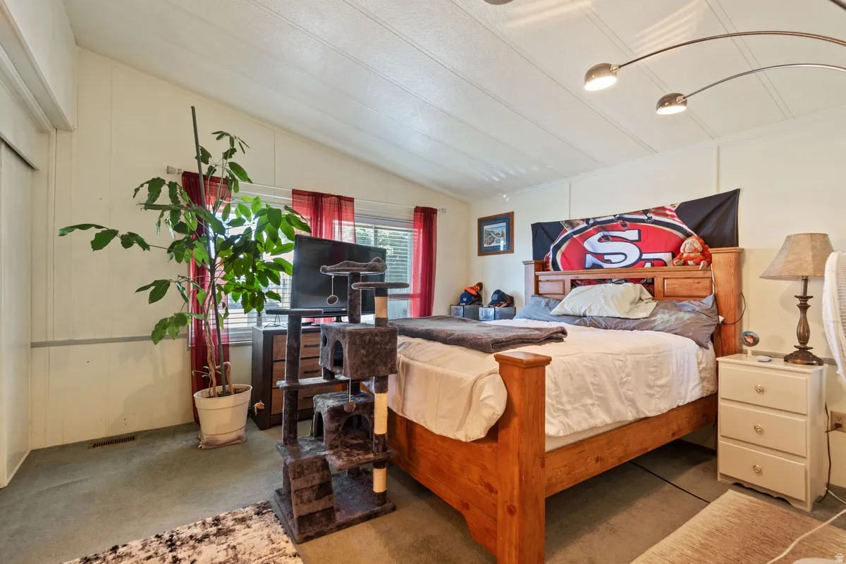 Spacious sleeping area featuring panel walls and a vaulted ceiling