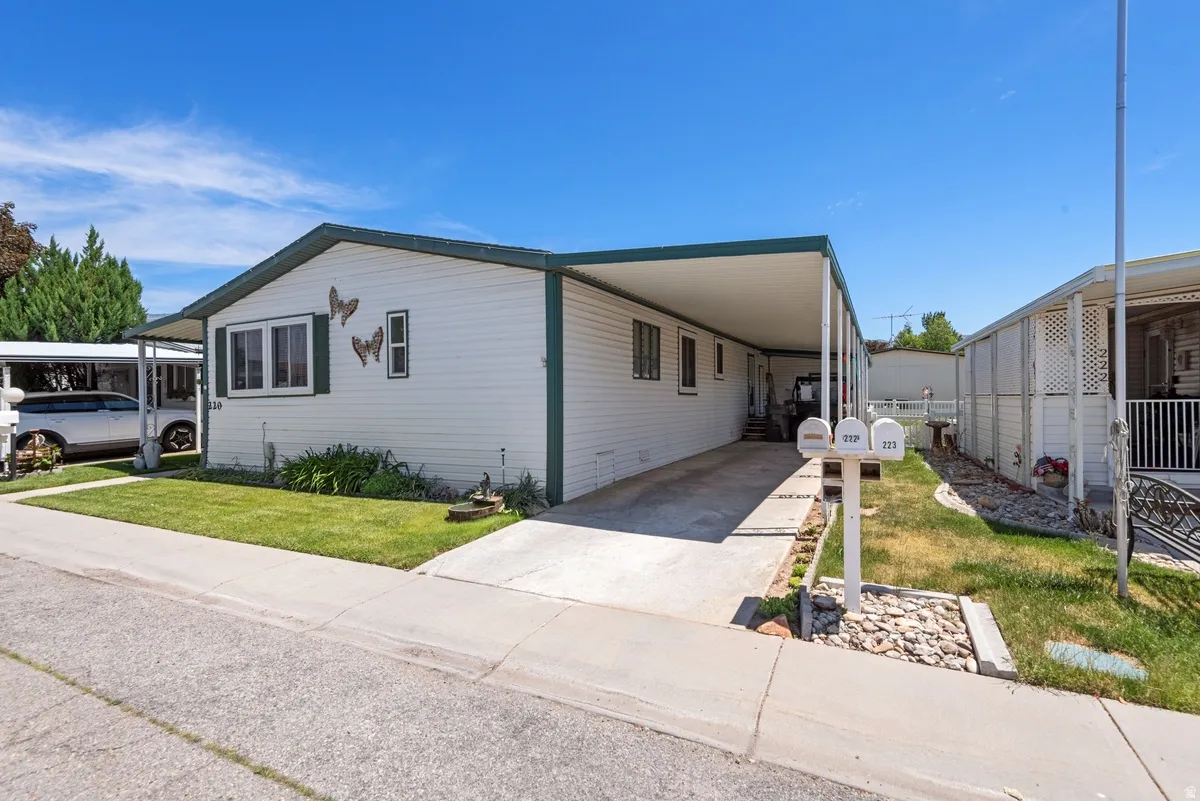 White horizontal siding exterior with dark green trim and a covered carport